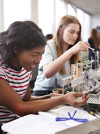 two girls showing excitement while working on an engineering project in class